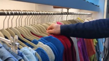 Woman pulling red clothing from hanger at store