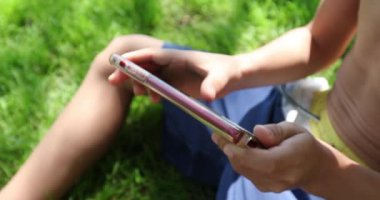 Child boy hands holding cellphone pressing screen playing games outdoors