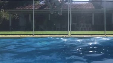 Child jumping inside swimming pool water going underwater in slow-motion