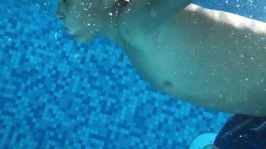 Child swimming inside pool, seen from underwater