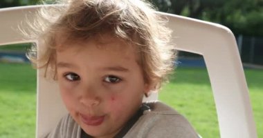 Child boy lookign to camera wanting to touch camera lens, covering it