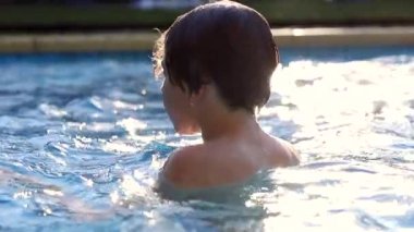 Kid at the swimming pool, young boy going underwater, diving
