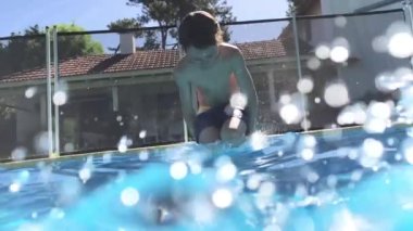 Child jumping inside swimming pool going underwater in super slow-motion
