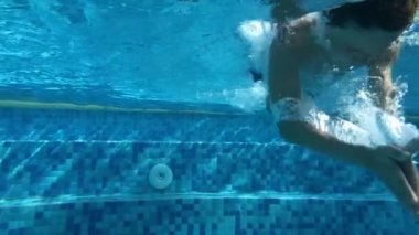 Child diving underwater inside swimming pool
