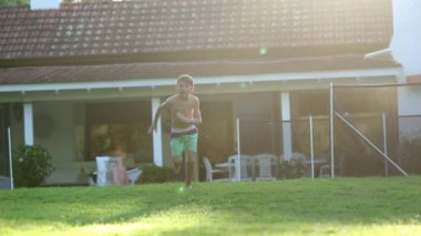 Kid runs outdoors in home garden