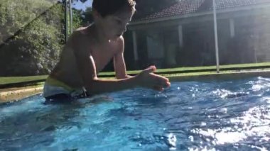 Kid diving inside blue clear swimming pool water