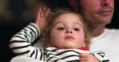 Kid playing with curly hair on father lap