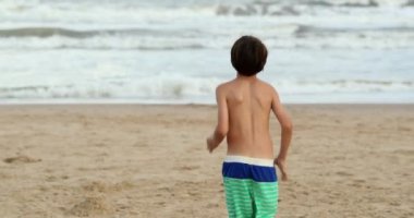 Child running towards water at beach