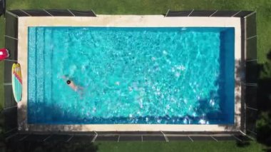 Vertical aerial perspective of child swimming inside pool