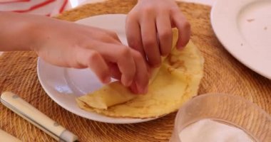 Kid hands rolling a crepe for breakfast