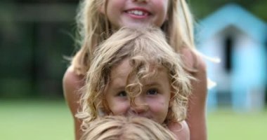 Küçük kız kardeşler fotoğraf için poz verir, kardeşler üst üste gelir.