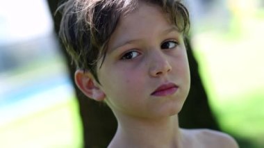 Portrait of handsome child outdoors, thinking, lost in thought