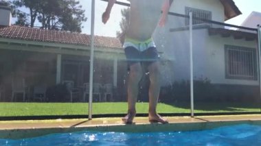 Child boy jumps into swimming pool water