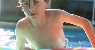 Yüzme havuzunda oynayan bir çocuk, yaz tatillerinde yakışıklı bir gencin portresi.