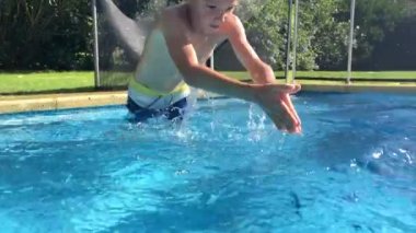 Child diving inside swimming pool water. Young boy kid dives into clear water