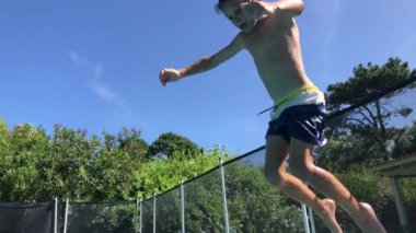 Child boy jumping inside swimming pool going underwater