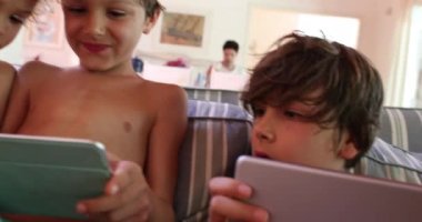 Çocuklar tablet tutuyor ve video oyunları oynuyorlar