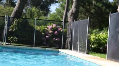 Young boy jumps inside swimming pool water during summer vacations