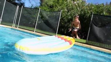 Child boy jumping on top of inflatable toy at the pool