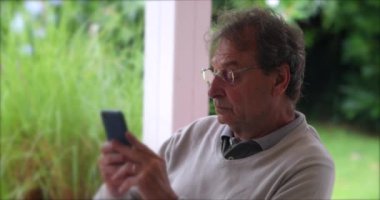 Candid older man using cellphone. Casual senior person browsing typing on smartphone