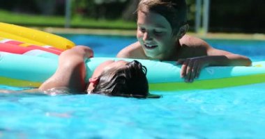 Havuzdaki çocuklar eğleniyor. Çocuklar şişme yatağın üstünde. Arkadaşlar birlikte.