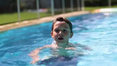 Young boy inside swimming pool water. Happy child enjoying pool