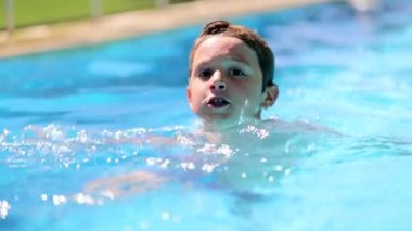 Casual candid child boy inside swimming pool water