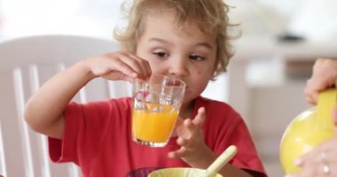 Feeding little boy. Child drinking orange juice breakfast
