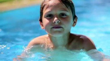 Portrait of child at the pool. Handsome young boy inside swimming pool water smiling to camera