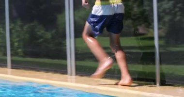 Young boy running by poolside
