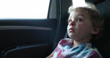 Passenger little boy in the back seat of a car traveling