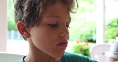 Little boy doing digust face and funny grimace and then taking a bite from food