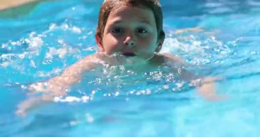 Child boy swimming at the pool. Young boy enjoying summer vacations