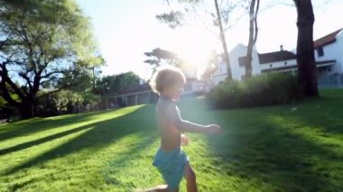 Child running outside in home garden with lens-flare