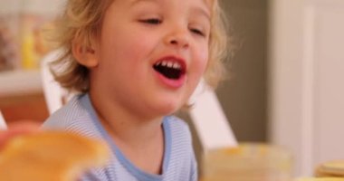 Candid infant toddler baby boy smiling and laughing seated at breakfast table