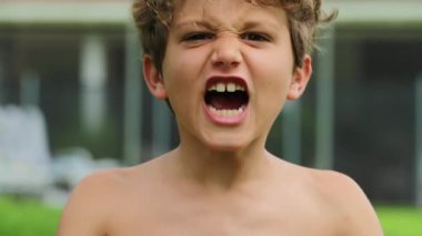 Child boy screaming from top of his lungs in slow-motion 120fps. Kid yelling roaring to camera