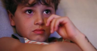 Casual Young boy watching TV screen. Kid caughs as he watches content