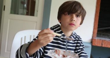 Little boy eating ice-cream dessert with spoon