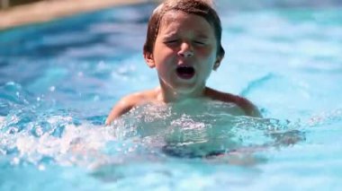 Handsome child boy inside swimming pool water. Kid enjoying summer vacations