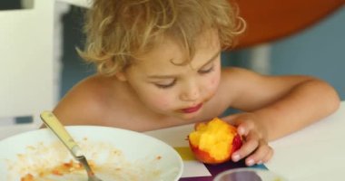 Baby toddler eating peach fruit, casual and candid