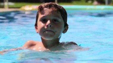 Child boy inside swimming pool water, enjoying summer vacations