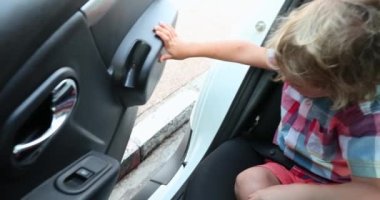 Child opening car door, removing seatbelt, stepping out of the car