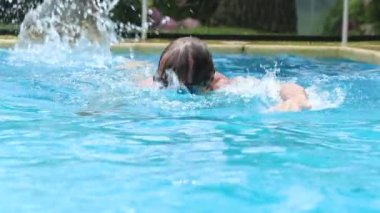 Elder man swims at the pool wearing goggles doing crawl cardio