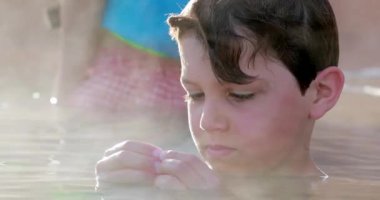 Ilık havuz suyunun içindeki çocuk, ısıtılmış su buharlaşıyor.