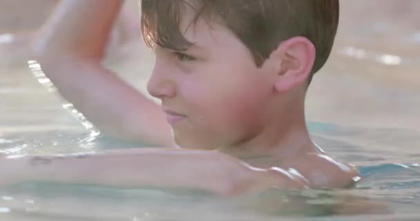 温水プールの水の中に何かを投げる子供 — ストック動画