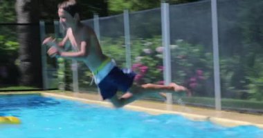 Young boy jumping into swimming pool water