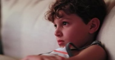 Child watching TV screen. Portrait close-up of young boy staring screen at night