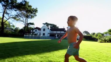 Toddler baby boy running outside in home garden with sunlight lens-flare shining