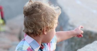 Cute Child boy pointing in the distance, wind blowing