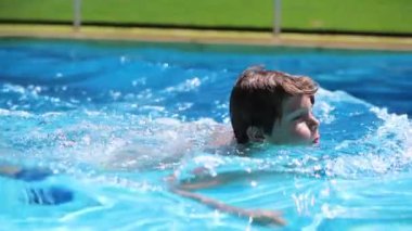 Child boy swimming in slow-motion. Young boy at the pool